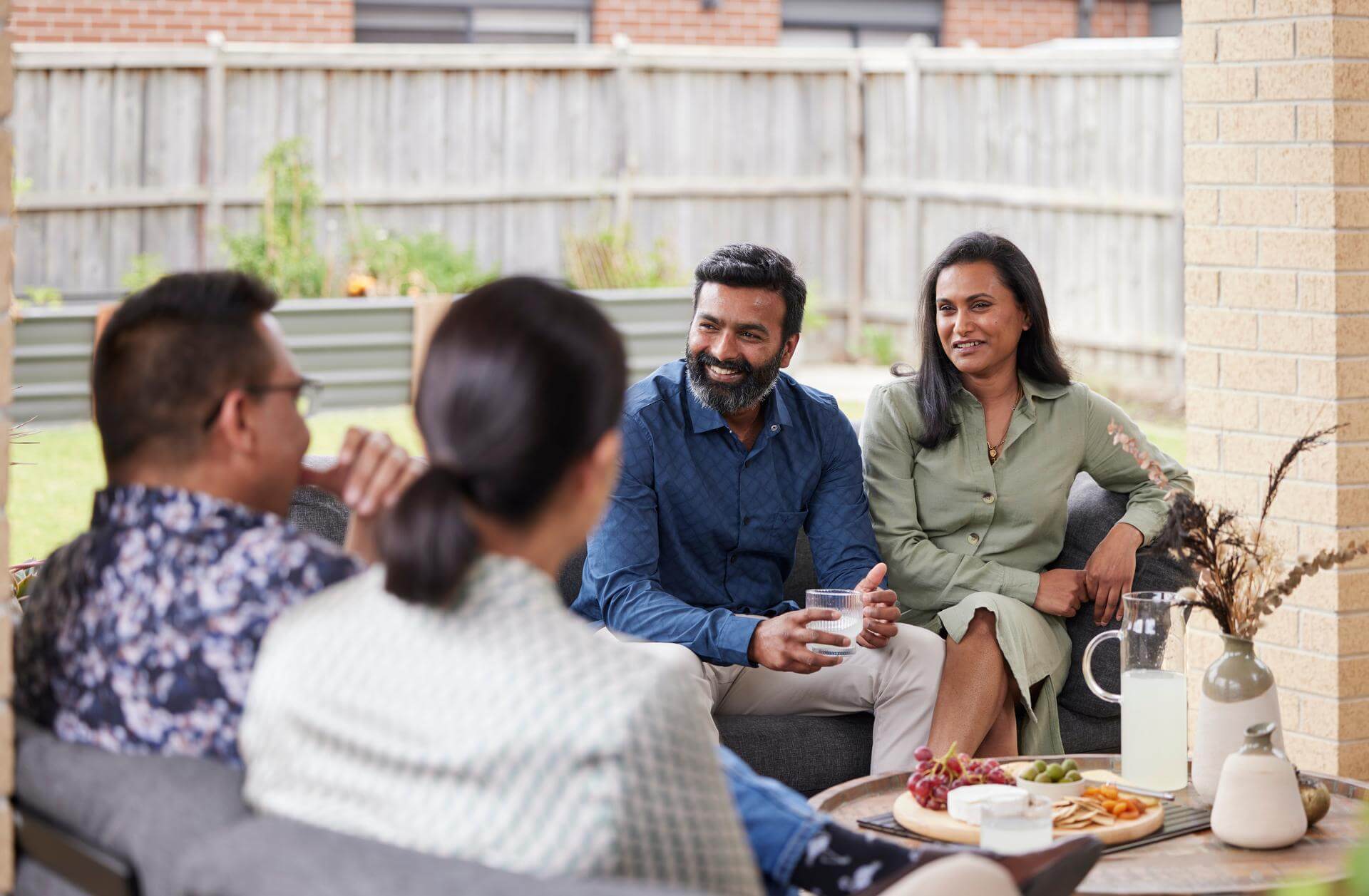 Couple smiling and talking to friends in backyard