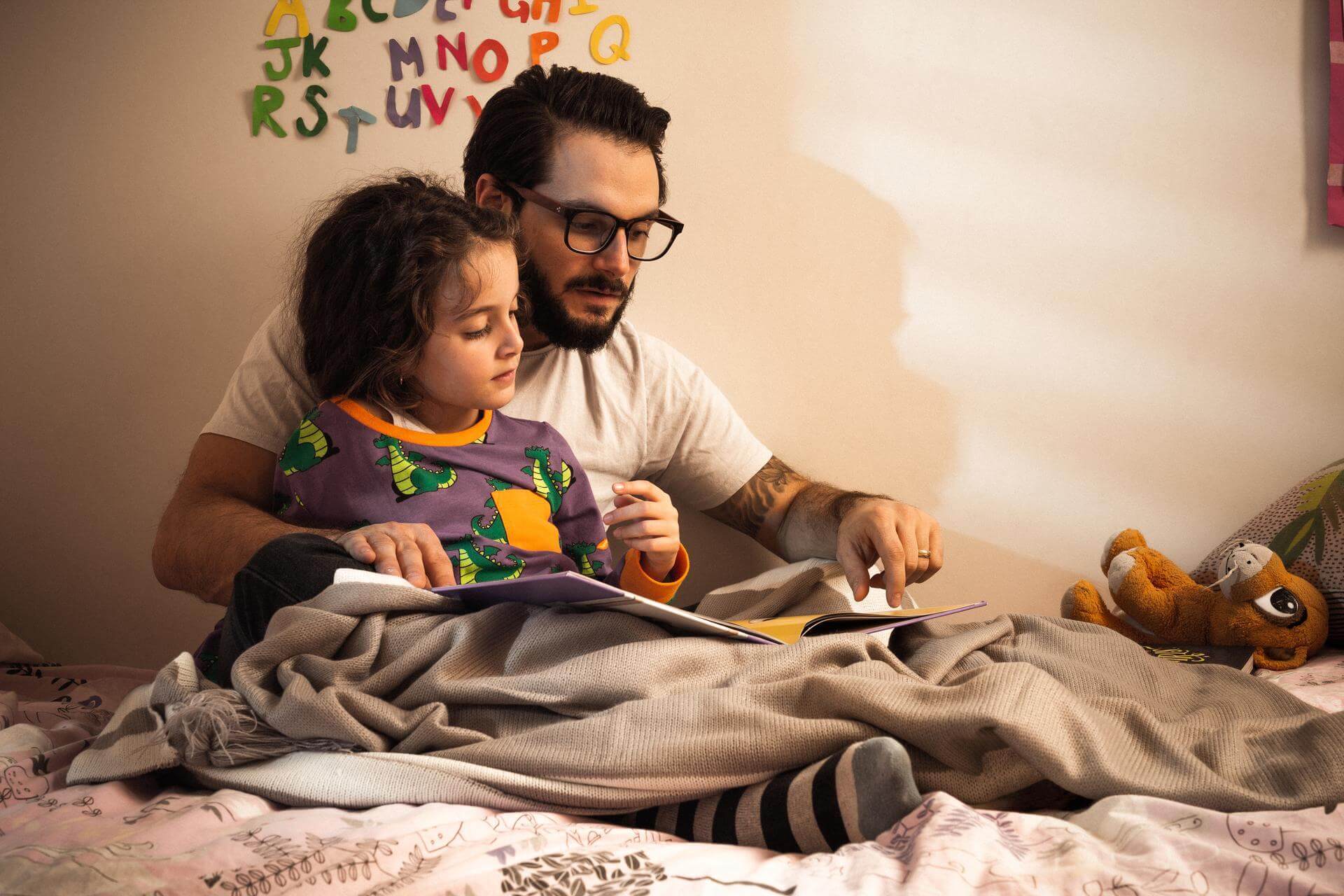 Father and child reading a book in cosy bedroom