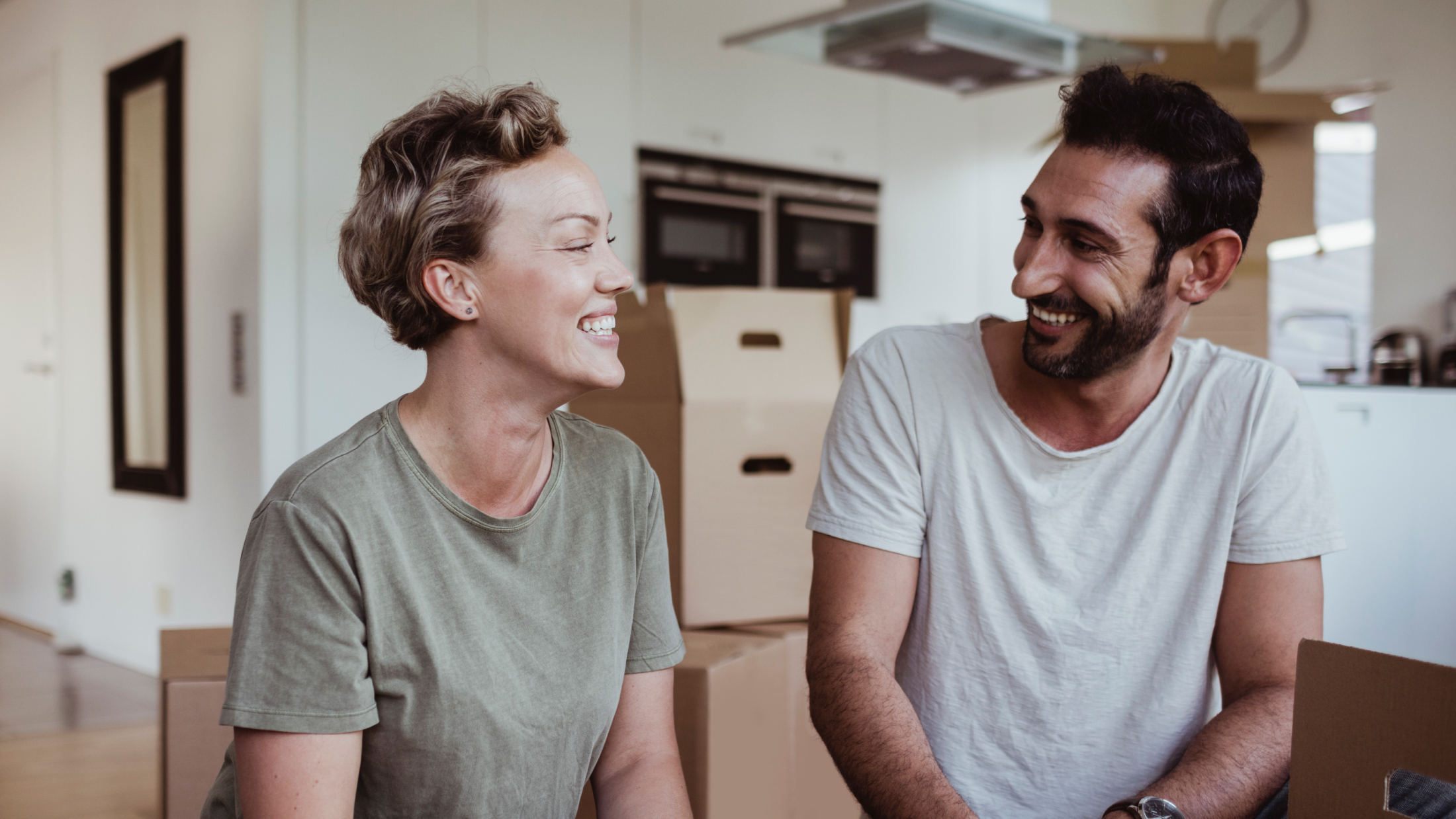 Man and woman laughing together surrounded by boxes in new home
