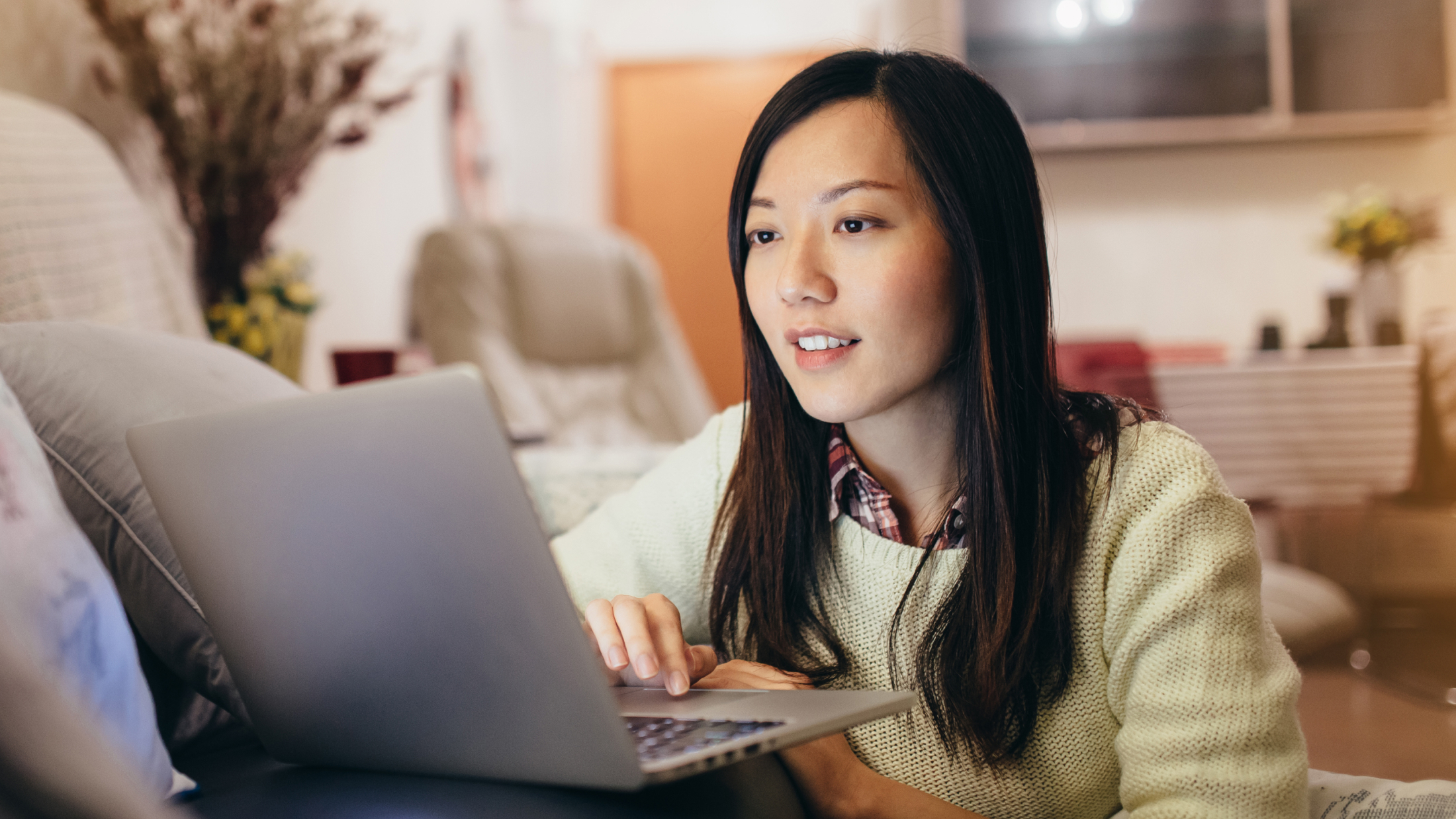 Woman sitting on floor on her laptop propped on couch