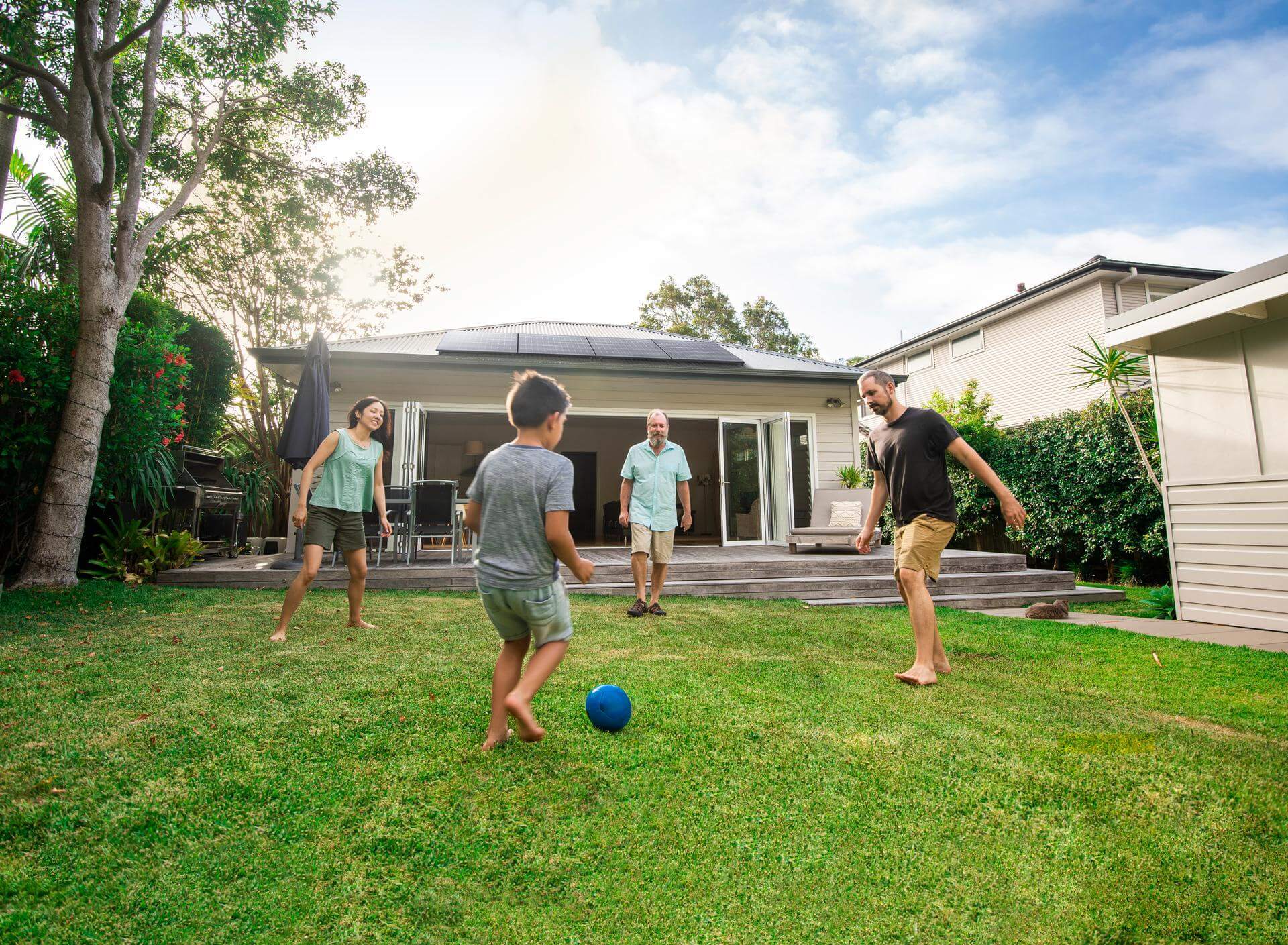 Family plays in their backyard with solar panels on the roof