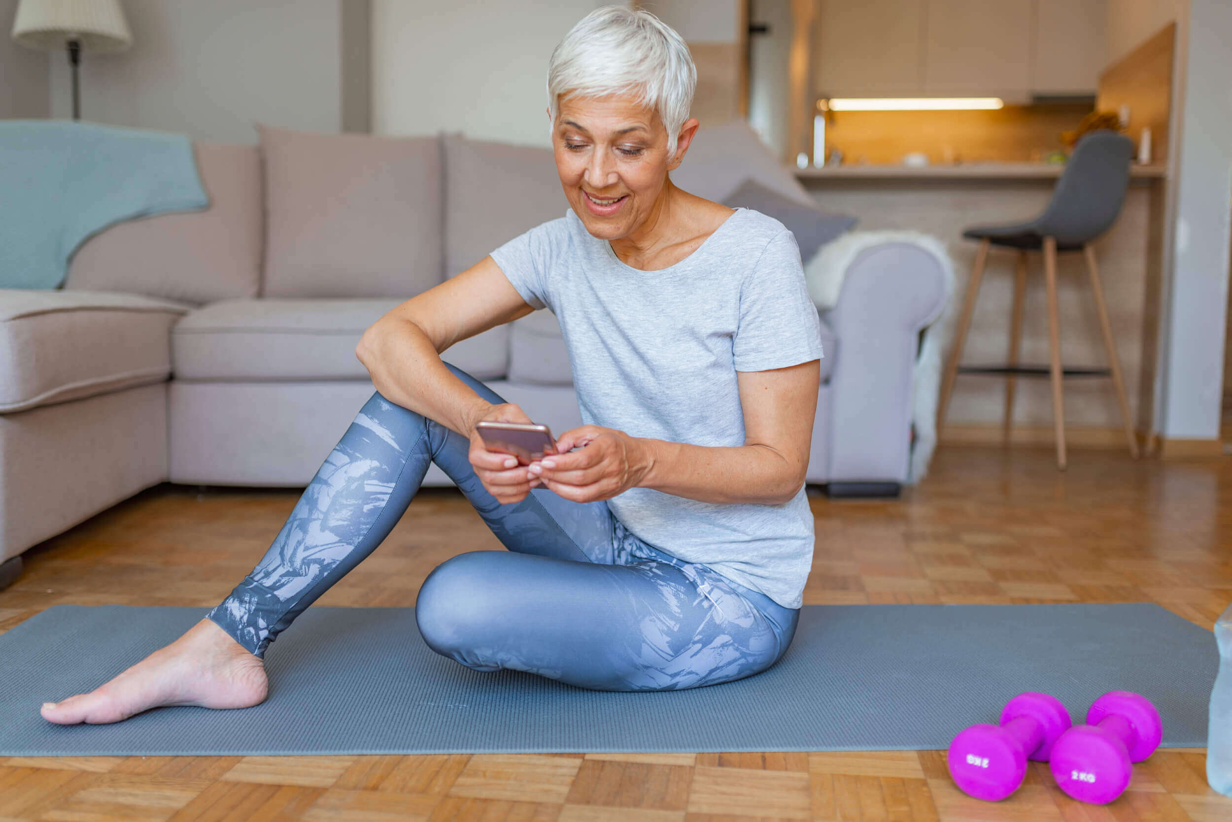 Woman on her phone doing a workout at home 1